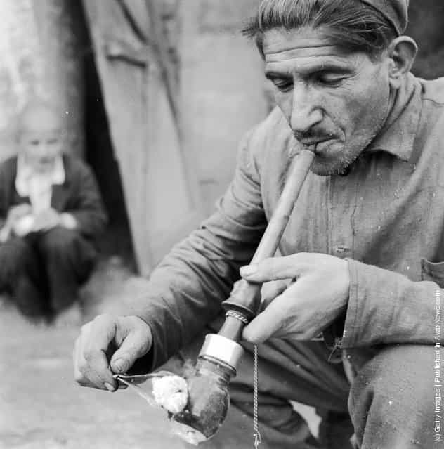 circa 1950: An Iranian smoking an opium pipe