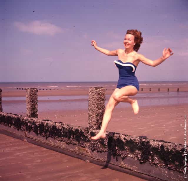 Marianne Brauns jumping a breakwater on the beach, 1950