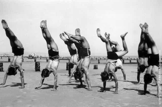 Boys doing handstands on the beach at a holiday camp, 1936