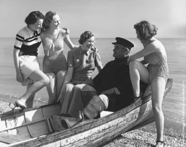 Bathing beauties cluster round a fisherman as he regales them with his fishy tales, 1939