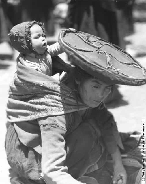 A mother in Peru binds her baby to her back as she works, 1947