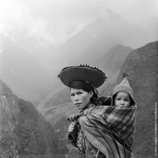 A Peruvian woman treks through the Andes carrying her baby on her back in a fold of her shawl, 1955