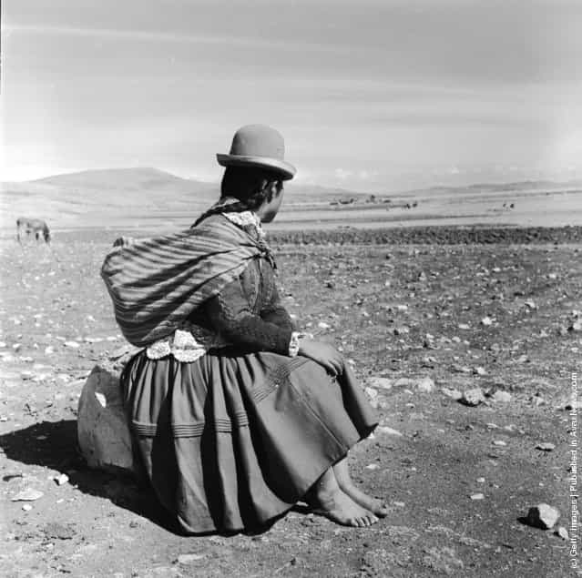 Burdened with a shawl full of her belongings, a woman stops for a rest on the road between Julaca and Puno in Peru, 1955