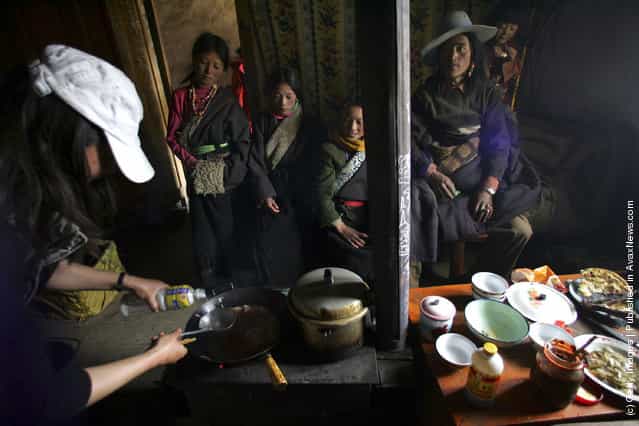 Tibetan students of the Xiangnong primary school watch a tourist to cook lunch