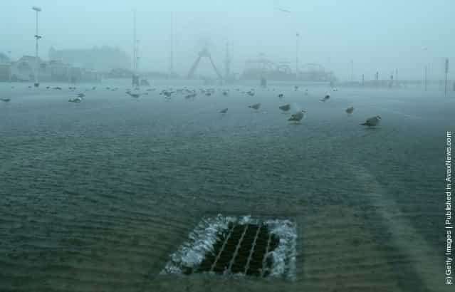 Water in a parking lot enters a storm drain as winds and high tides from approaching Hurricane Irene