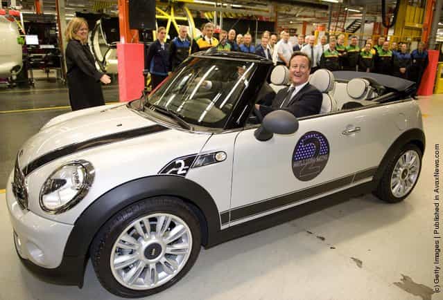 British Prime Minister David Cameron, beside BMW group management member for production Frank-Peter Arndt, drives the two millionth MINI off the production line