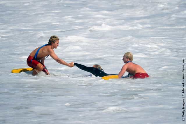 Lifegaurds help pull a woman out of the ocean as high waves measuring up to 20 feet pounded the beach at the Wedge