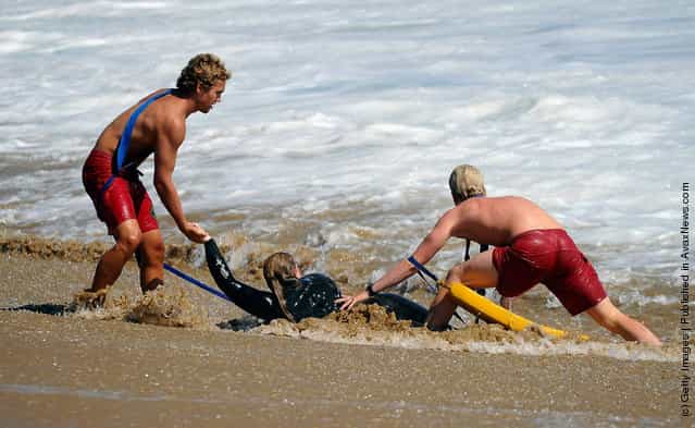 Lifegaurds help pull a woman out of the ocean as high waves measuring up to 20 feet pounded the beach at the Wedge