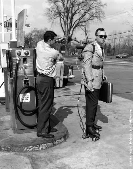 Salesman has his motorised roller skates refuelled at a petrol station near Hartford, Connecticut
