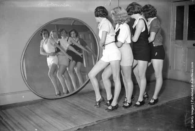 1935: Students at a dance school dancing in front of a large, round mirror