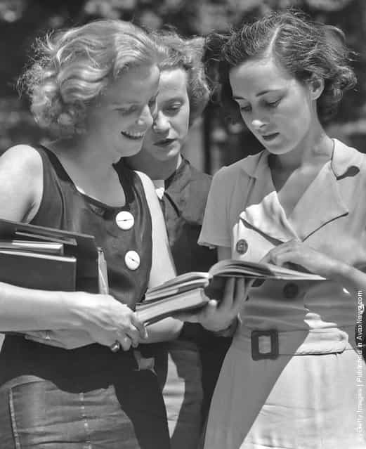 Three female students reading a book circa 1950s