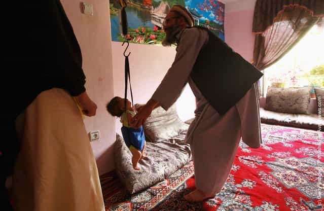 An Afghan vollunteer weighs a child at a USAID-funded health help center