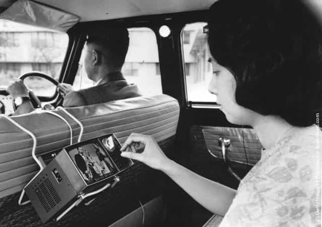 1963: A woman uses a new portable micro television, invented by the Japanese Sony Company, in the back of a car