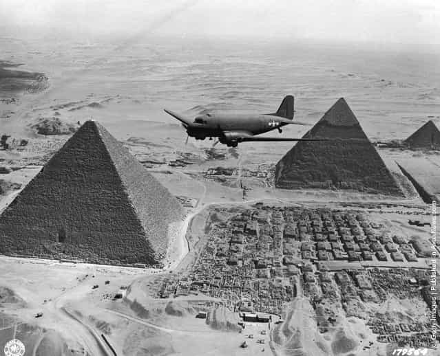 1943: A Dakota air transport plane of the US Army Air Force flies over the pyramids in Egypt, loaded with urgent war supplies