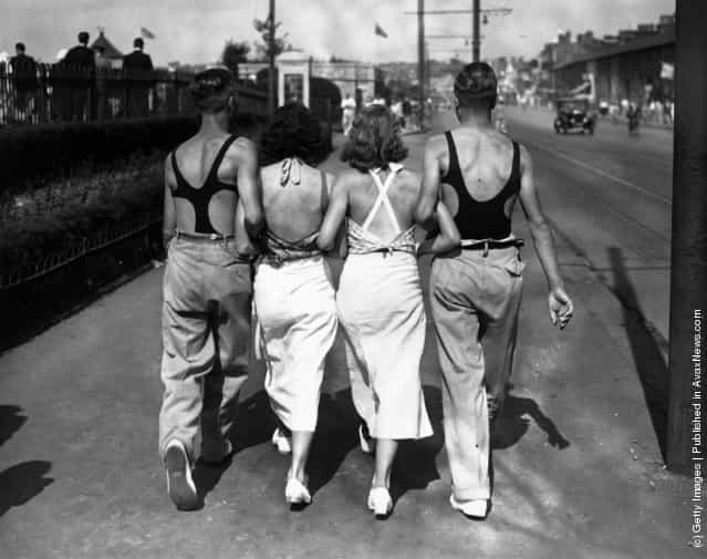 Four young people in swimming costumes walking along arm in arm at Thorpe Bay, Essex, England, 1934