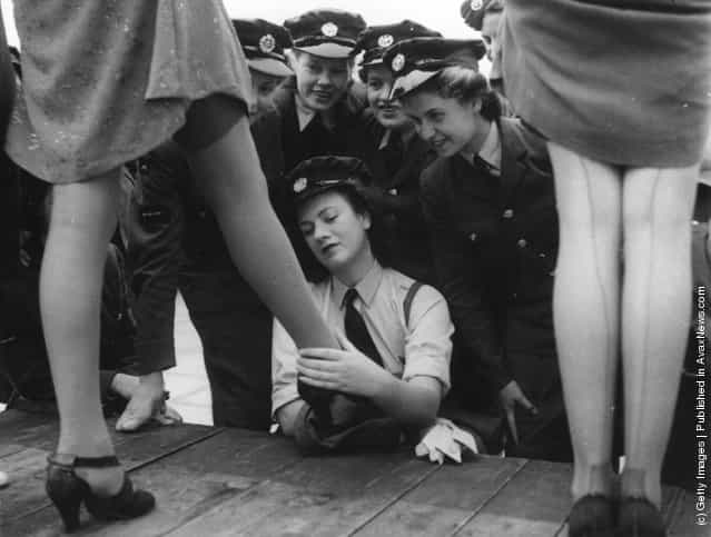 1943: Servicewomen look at a design of artificial silk-plated stocking, called 731, specially designed for servicewomen at a fashion show at Kennards of Croydon