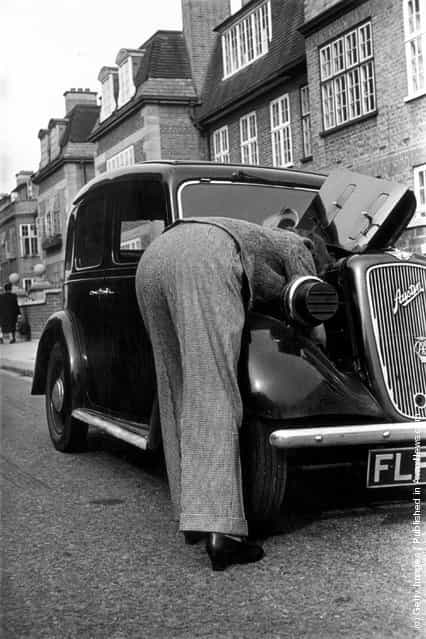 1941: This woman enjoys the practicality of the new fashionable trousers for ladies leaning into the bonnet of her Austin motor car