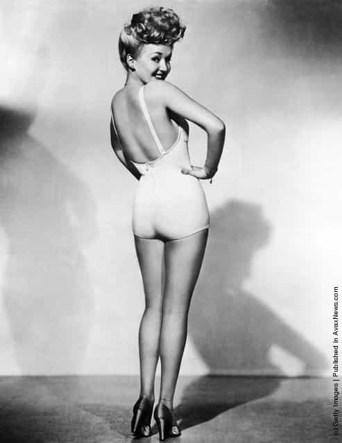 Portrait of American model and actress Betty Grable, as she stands in high heels and a one-piece bathing suit and looks over her shoulder, one hand on her waist, 1943