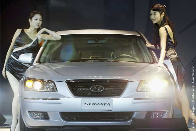 Models pose next to the new mid-sized sedan 'NF Sonata' unveiled by Hyundai Motor