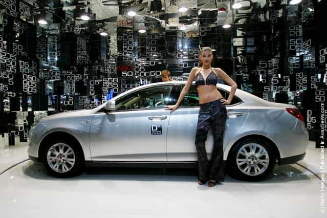 Models pose beside the world premiere display of the Roewe 550 during a special media opening of the Auto China 2008 show