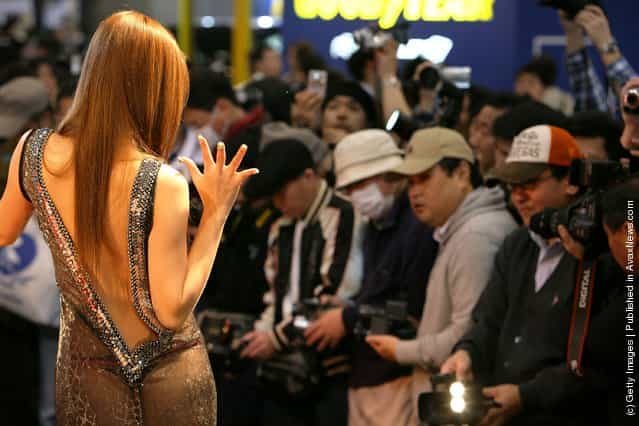 A model poses with a customized Chrysler 300c displayed at a booth while visitors take pictures at Tokyo Auto Salon 2009
