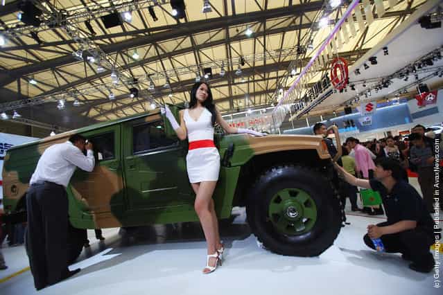A model poses next to Dongfeng Motors High Mobility Mutlpurposc Wheeled VehicleЈ HMMWVЈ
