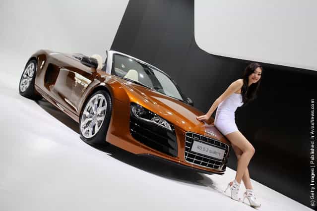 A sexy model stands beside Audi R8 5.2 quattro car