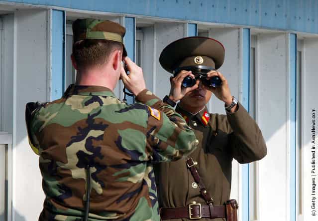 A U.S. soldier (L) takes picture of a North Korean soldier as he stands guard