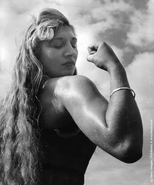 1953: Twenty-one year old Alice Penfold, a professional strong woman from Bury, near Pulborough, Sussex, flexes her biceps
