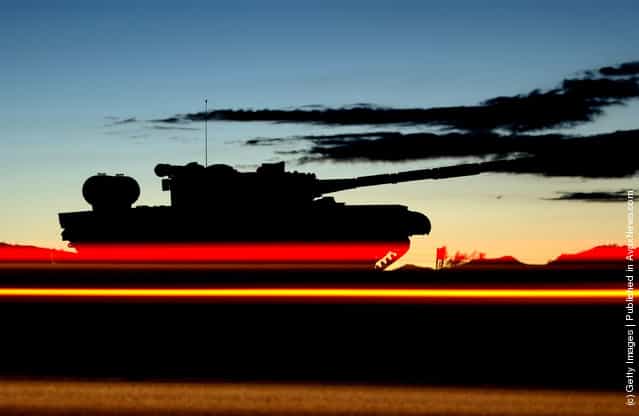 Morning commuter tail lights streak past a tank on display at the entrance to the U.S. Armys Fort Irwin Military Reserve