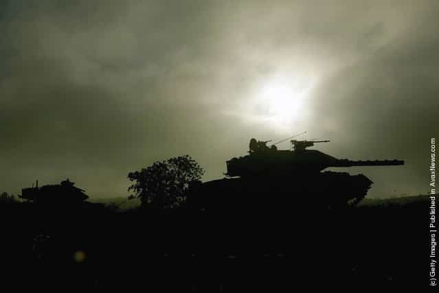 Israeli army Merkava tanks are silhouetted against the morning sun