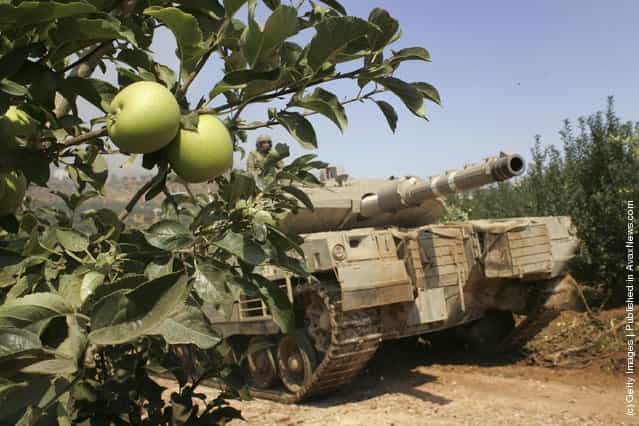 An Israeli tank moves through an apple orchard before entering Lebanon from the Israel Lebanese border