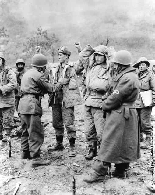 Turkish UN troops search captured Chinese troops for weapons during the Korean War