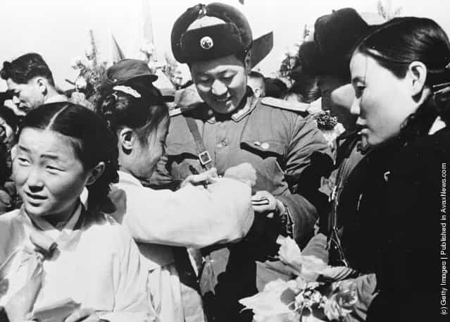 1958: Korean girls present a member of the Chinese Peoples Volunteer Army with a bouquet of flowers prior to the mass withdrawal of Chinese troops from North Korea