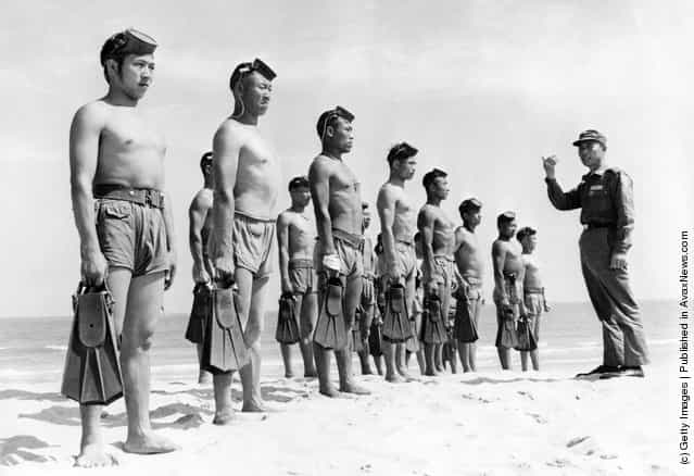 A line of Nationalist Chinese Frogmen, who form the Silent Service of the Quemoy Defence Command, wearing army shorts and holding pairs of fins are briefed by one of their commanding officers on a Quemoy beach