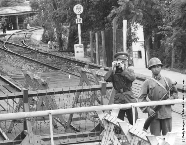 1965: A Red Chinese guard at Luhu Bridge, Hong Kong, takes a photograph of the photographer for official files