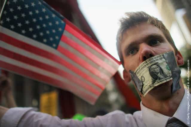 A protester wears a dollar bill over his mouth at the start of a march by demonstrators opposed to corporate profits on Wall Street