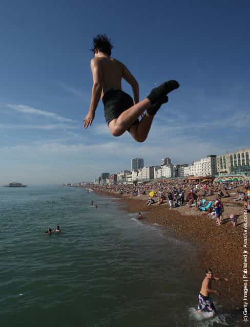 A youth jumps into the water from a sea wall