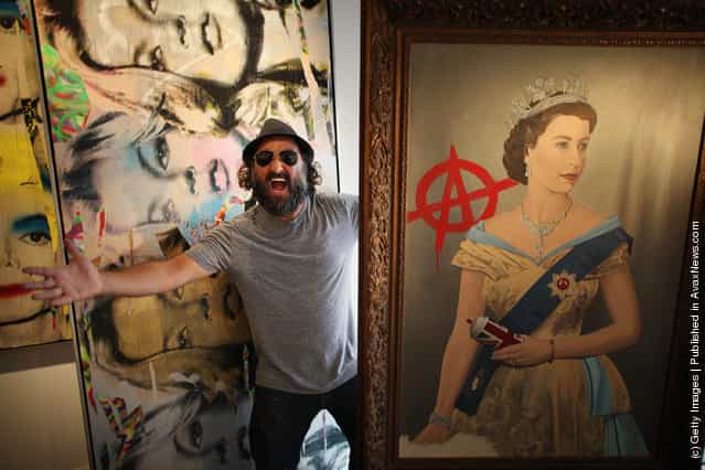 Artist Mr Brainwash stands with his paintings The Queen (R) and Kate Moss at the Opera Gallery
