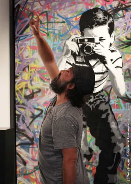 Artist Mr Brainwash stands in front of his painting Smile at the Opera Gallery