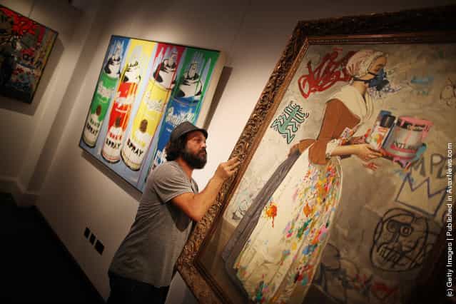 Artist Mr Brainwash helps to hang his painting Chocolate Vandal at the Opera Gallery