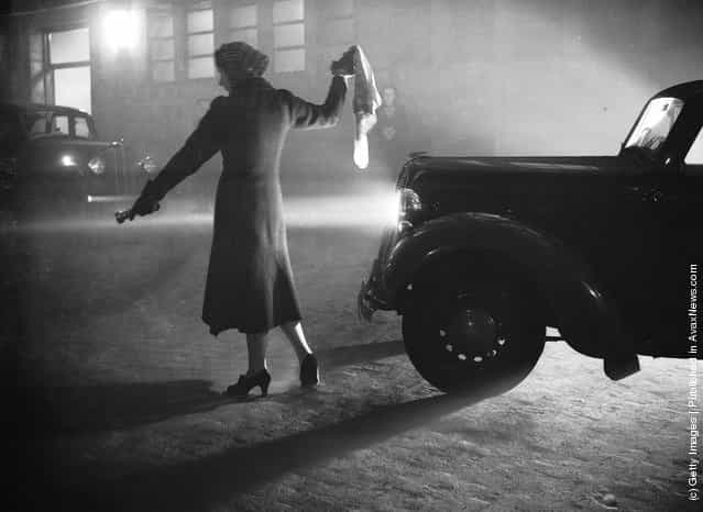 1938: A woman leads a car through Londons Regents Park with a torch, during the thick fog with visibility reduced to a few yards