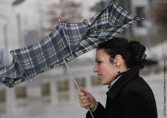 A woman holds on to her umbrella despite strong winds