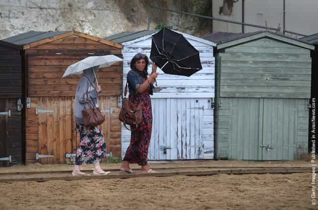 Women struggle with their umbrellas in high wind and rain on Viking Bay beach
