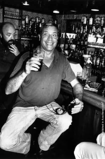 1984: Film star Oliver Reed pulls a face for the photographer while enjoying a pint of beer in a well stocked bar