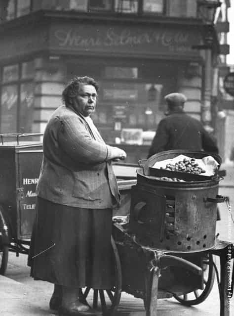 1935: A miserable looking woman selling hot chestnuts in a Soho street