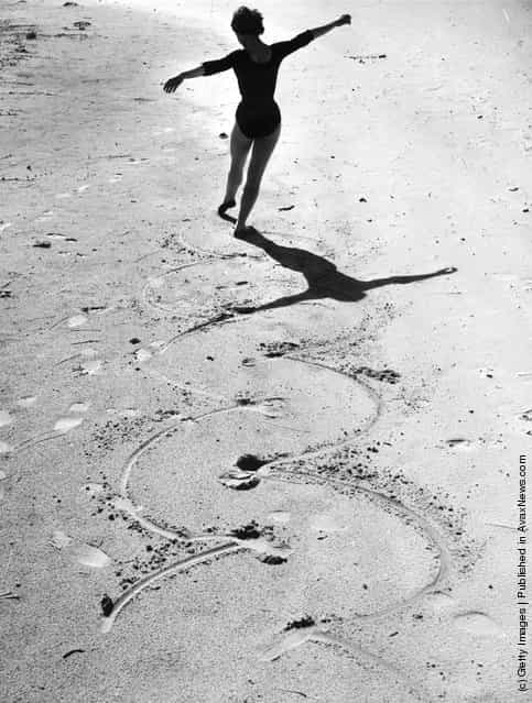 1955: A ballet dancer draws circles in the sand with the points of her toes