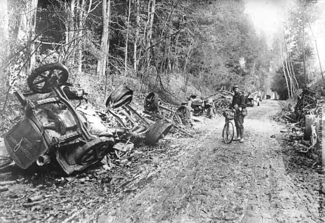 1914: A lone soldier with a bicycle stands amid the remains of a German motor convoy which lines a country lane after an attack by French field guns in the battle of the Aisne in France