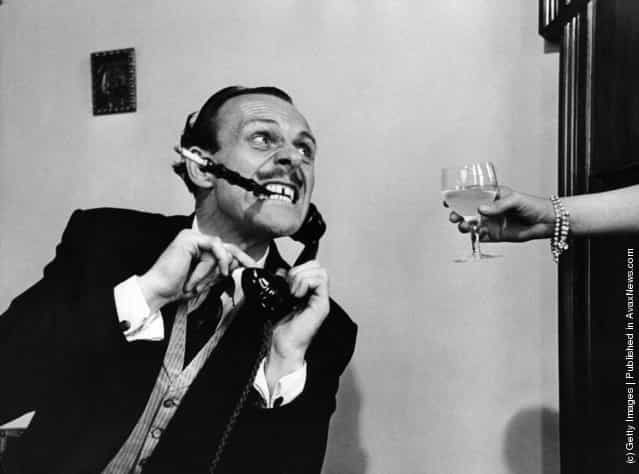 1954: English actor-comedian Terry Thomas, real name Thomas Terry Hoar-Stevens, demonstrates how an exhausted husband slaves late into the night, to keep his wife in idleness and luxury