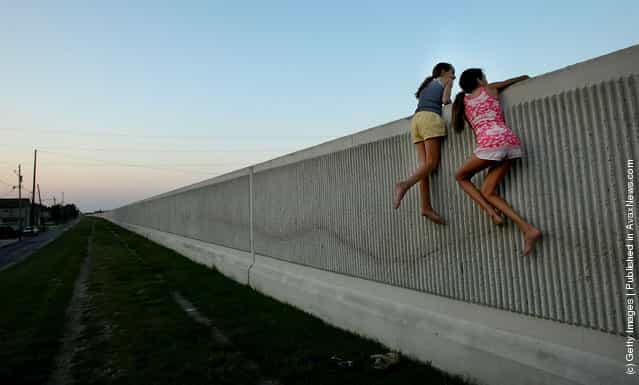 Isabella Lander (L) and Arabella Christiansen climb on the 17th Street Canal levee